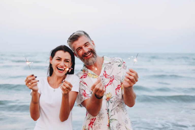 Best Places To Go for the Fourth of July Getaways in Texas: Two people are holding sparklers on the beach.
